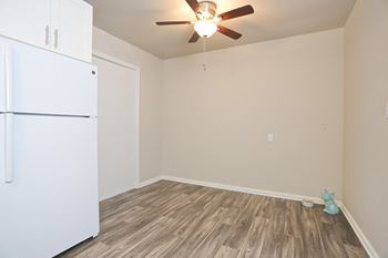 An empty room with a refrigerator and a ceiling fan